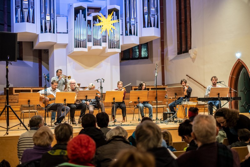 Auf der Bühne der Konzerthalle Ulrichskirche sitzen oder stehen acht Personen, sie musizieren mit unterschiedlichen Instrumenten. 